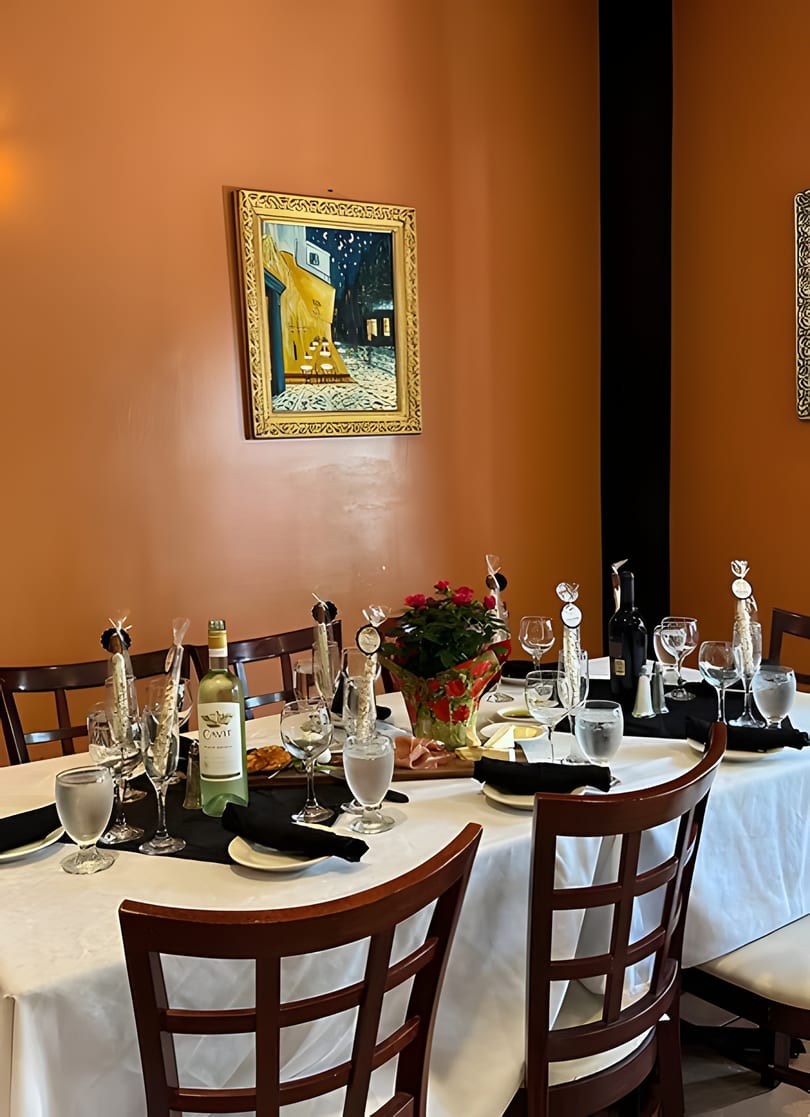 A dining table set with white and red wine, glasses, appetizers, and a floral centerpiece.